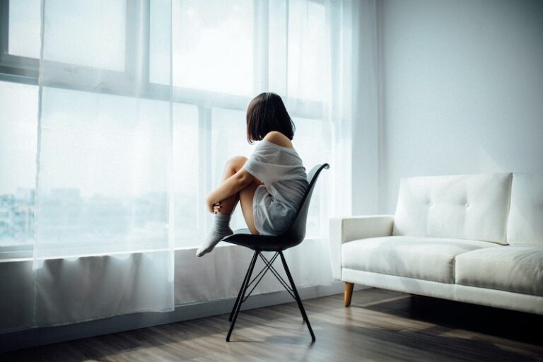 Woman sitting alone in a chair, looking out the window